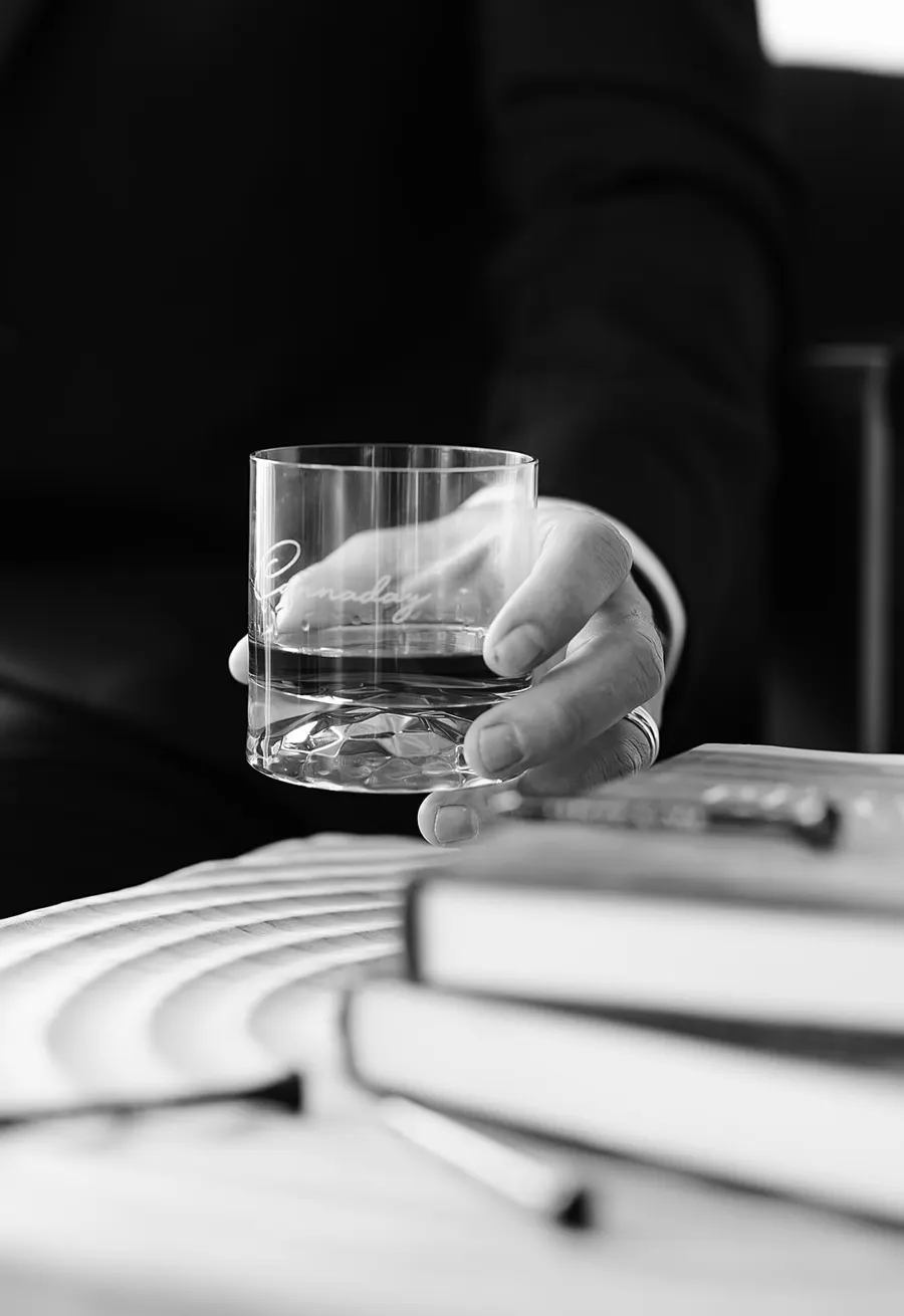 A glass in hand above a stack of books
